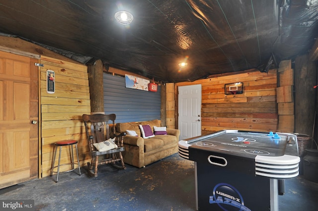 recreation room with concrete flooring and wooden walls