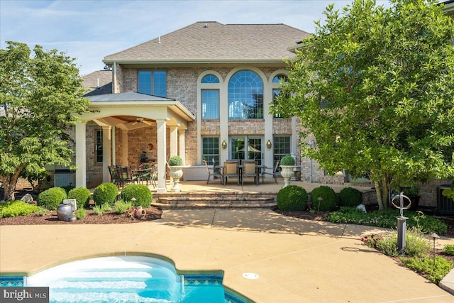 rear view of property with a patio, a shingled roof, an outdoor pool, brick siding, and ceiling fan