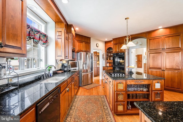 kitchen featuring a kitchen island, black appliances, sink, a wealth of natural light, and light wood-type flooring