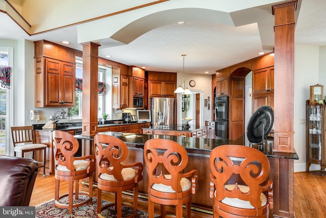 kitchen with stainless steel fridge with ice dispenser, a center island, light wood-style flooring, and dobule oven black