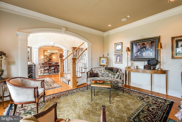 living room with ornamental molding, a notable chandelier, wood-type flooring, and decorative columns