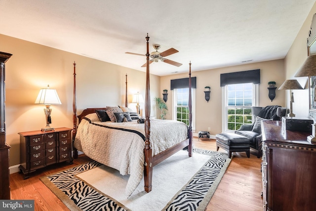 bedroom with a ceiling fan, visible vents, wood finished floors, and baseboards