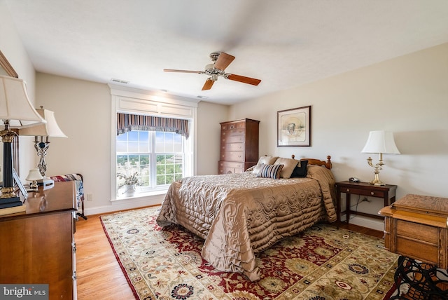 bedroom featuring visible vents, baseboards, ceiling fan, and light wood finished floors