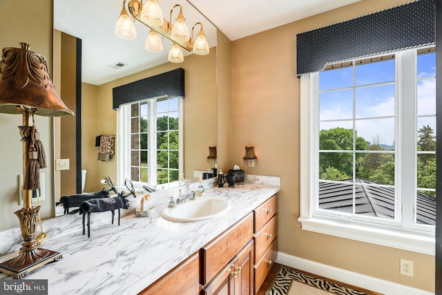 bathroom featuring vanity, baseboards, visible vents, and a chandelier