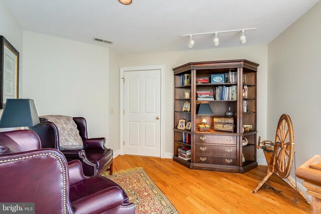 living area with light hardwood / wood-style flooring and track lighting