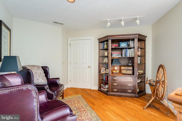 living area featuring visible vents, light wood-type flooring, and baseboards