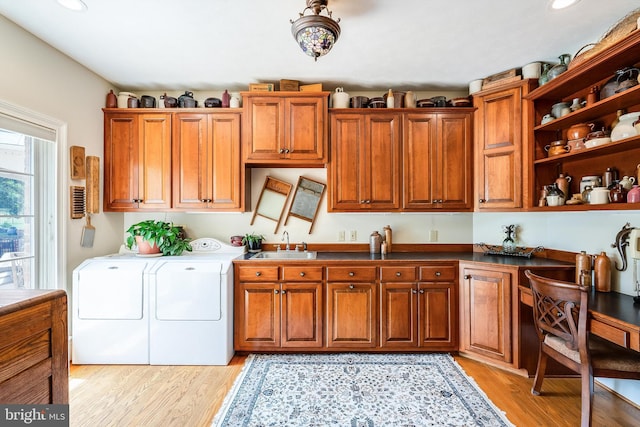 washroom with sink, light hardwood / wood-style floors, cabinets, and washing machine and dryer