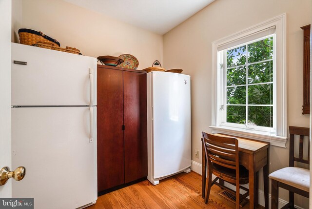 kitchen with white refrigerator, a healthy amount of sunlight, and light hardwood / wood-style floors