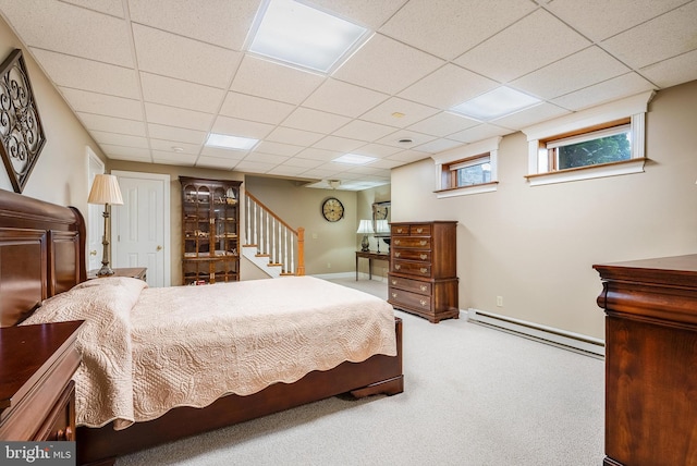 carpeted bedroom with baseboard heating and a drop ceiling