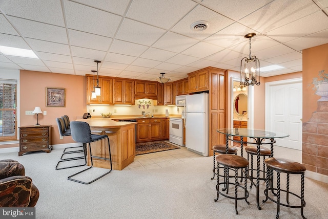 kitchen featuring light carpet, visible vents, white appliances, and a peninsula