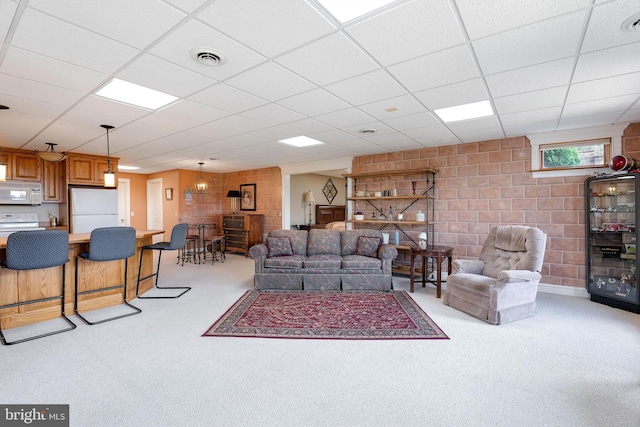 living area featuring a drop ceiling, visible vents, light colored carpet, and concrete block wall