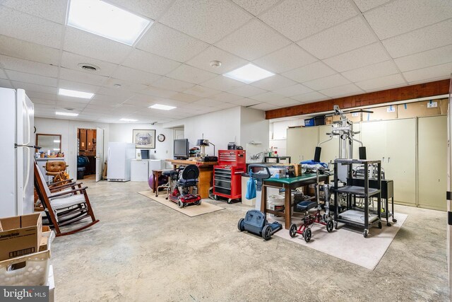 basement featuring white refrigerator and a drop ceiling