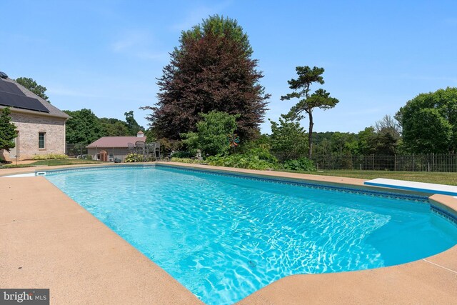 view of swimming pool featuring a diving board