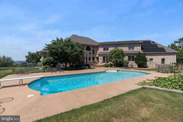 view of pool featuring a lawn, a diving board, and a patio area