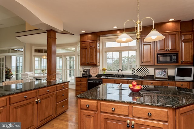 kitchen featuring brown cabinets, dark stone counters, a sink, light wood-style floors, and black appliances