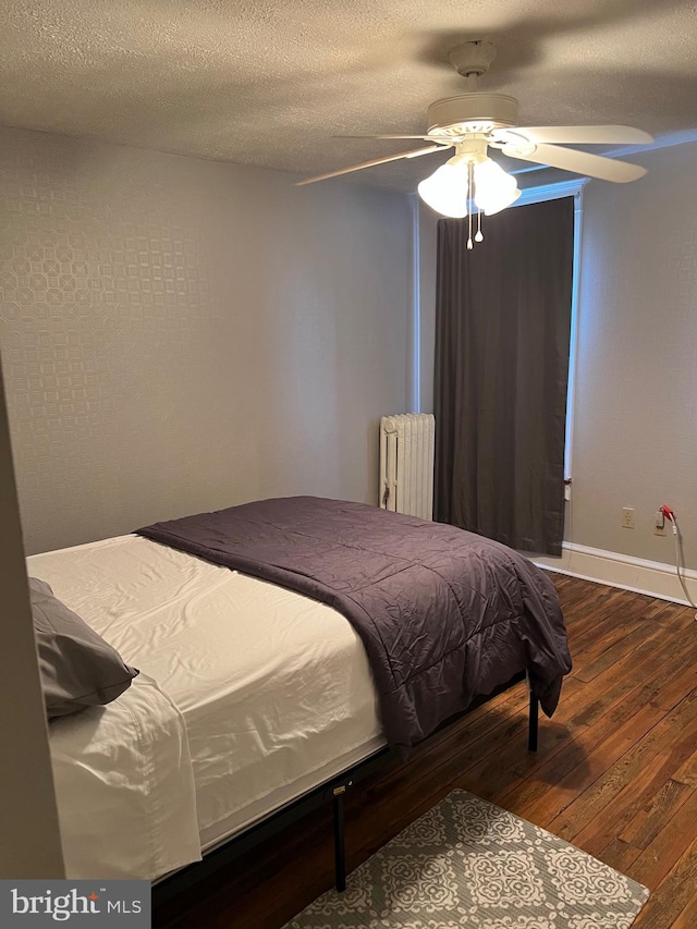 bedroom featuring radiator heating unit, a textured ceiling, ceiling fan, and wood-type flooring