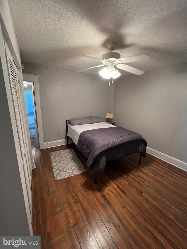 bedroom with a textured ceiling, ceiling fan, and dark wood-type flooring