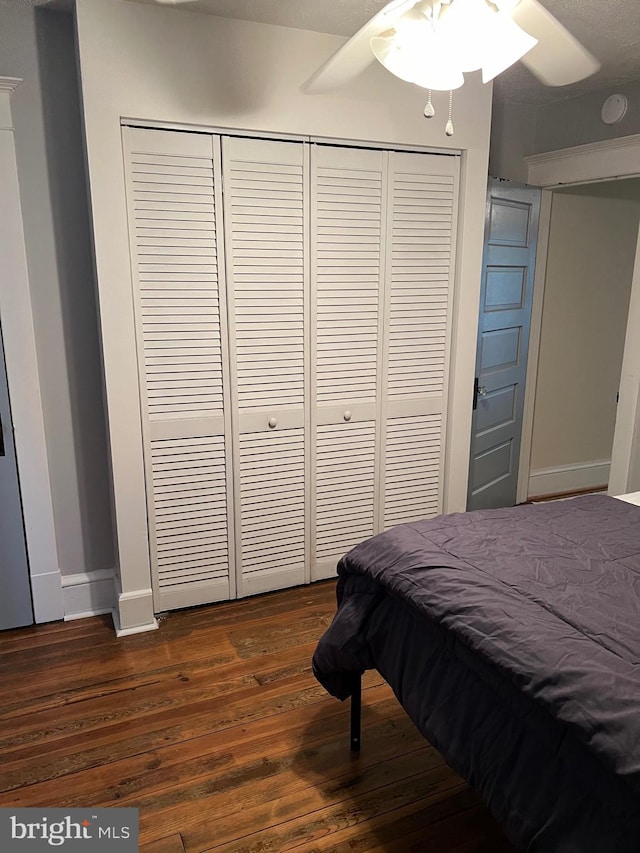 bedroom featuring ceiling fan, dark hardwood / wood-style floors, and a closet