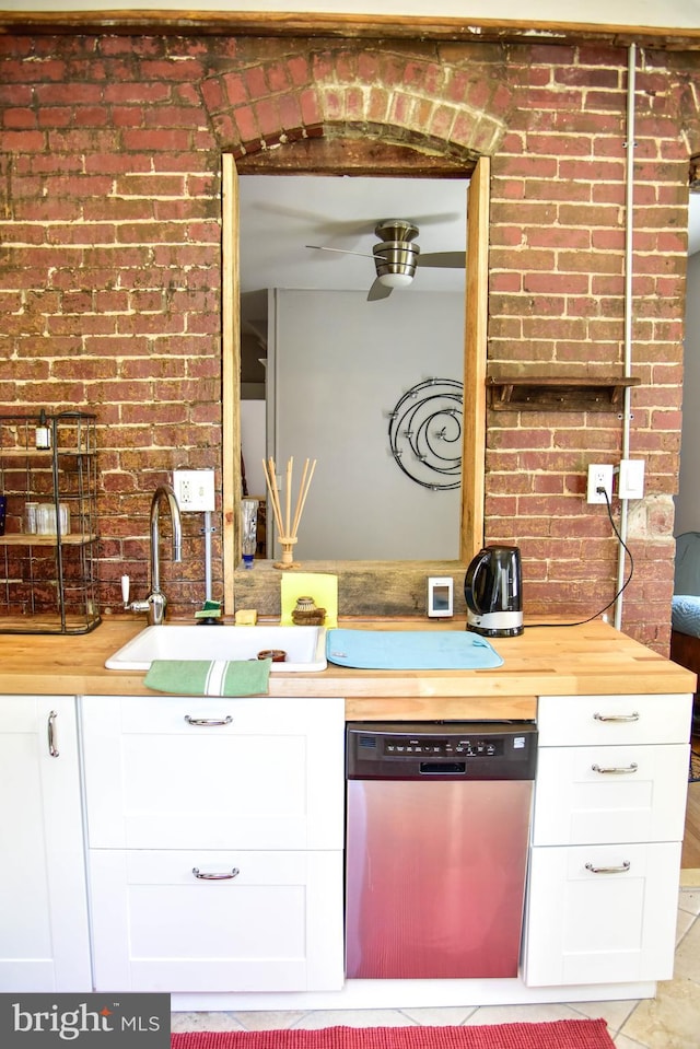 kitchen featuring sink, white cabinets, brick wall, and dishwasher