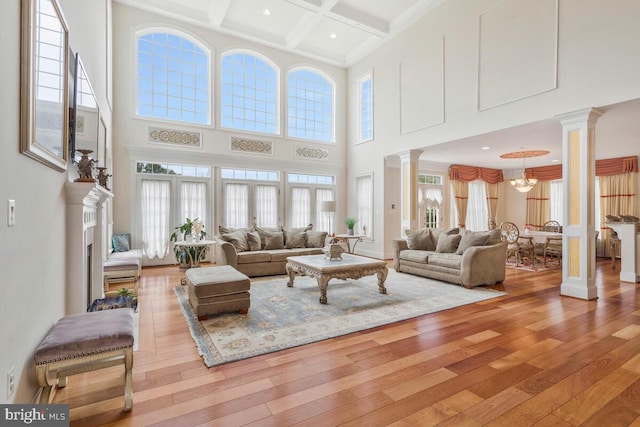 living room with beamed ceiling, light hardwood / wood-style flooring, coffered ceiling, and plenty of natural light