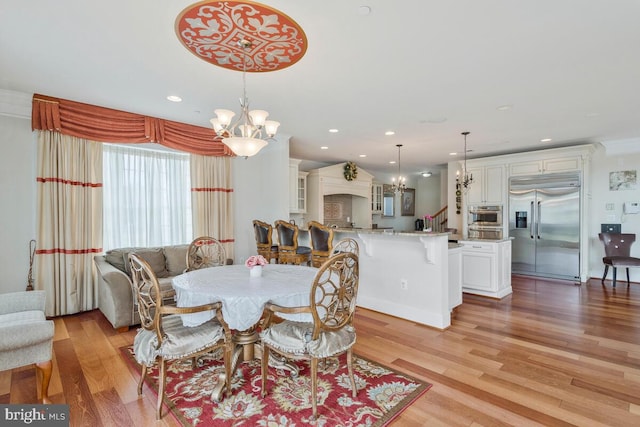 dining room with light hardwood / wood-style floors, a notable chandelier, and ornamental molding