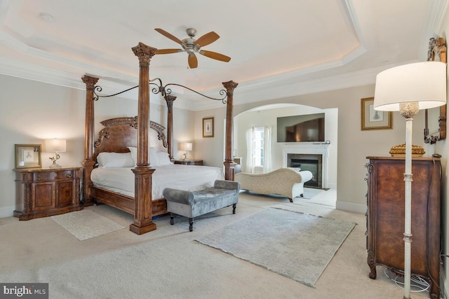 bedroom featuring light carpet, a raised ceiling, crown molding, and ceiling fan