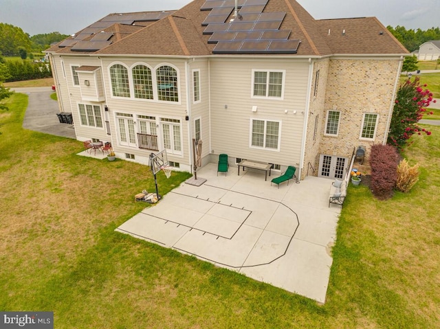 rear view of house with solar panels, a patio area, and a yard