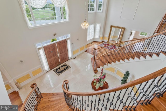 foyer entrance featuring a towering ceiling, hardwood / wood-style floors, and a wealth of natural light