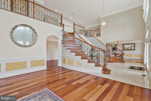 foyer with a towering ceiling, hardwood / wood-style floors, and ornamental molding