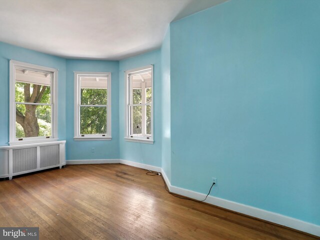 unfurnished room featuring hardwood / wood-style flooring, a paneled ceiling, and radiator