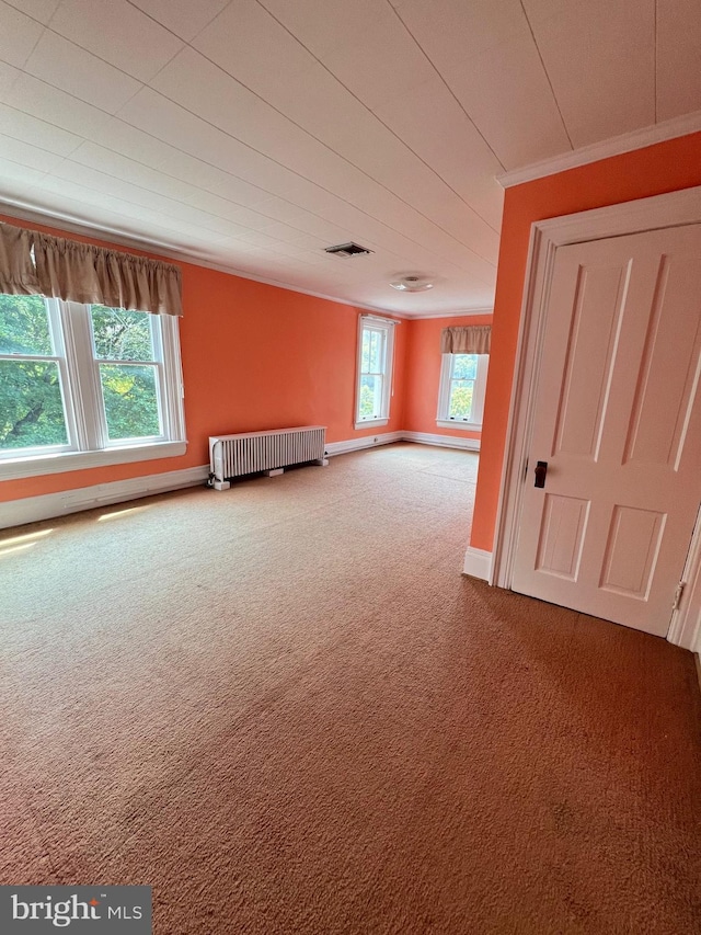 carpeted empty room featuring crown molding and radiator heating unit