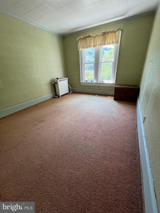 spare room featuring crown molding, radiator heating unit, and carpet floors