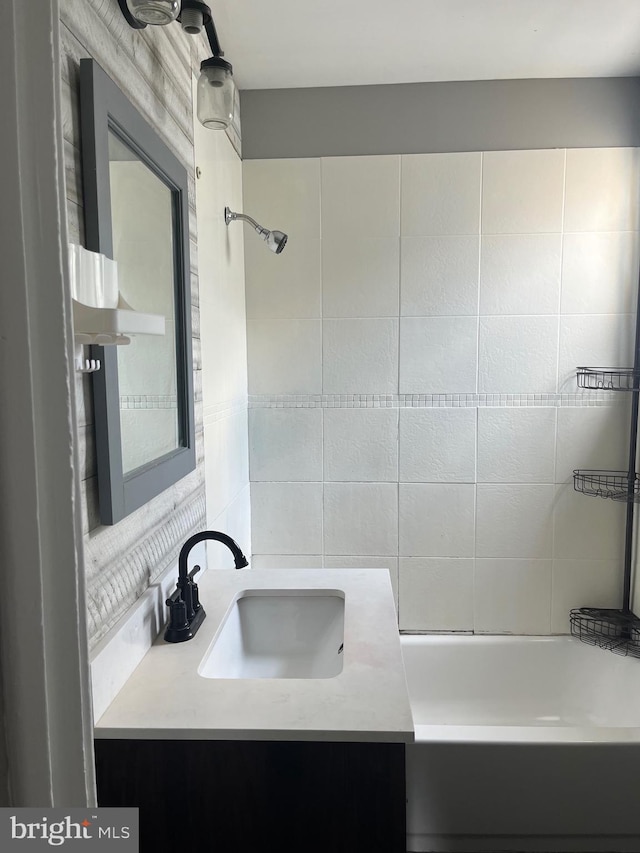 bathroom with vanity, tiled shower / bath combo, and backsplash