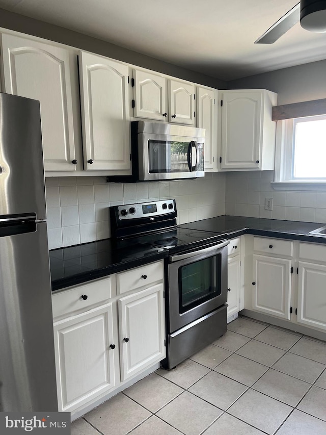 kitchen featuring white cabinetry, light tile patterned floors, ceiling fan, stainless steel appliances, and decorative backsplash