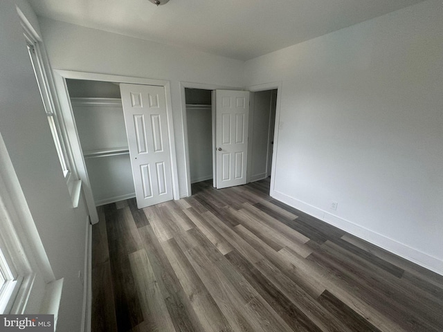 unfurnished bedroom with dark hardwood / wood-style floors and two closets