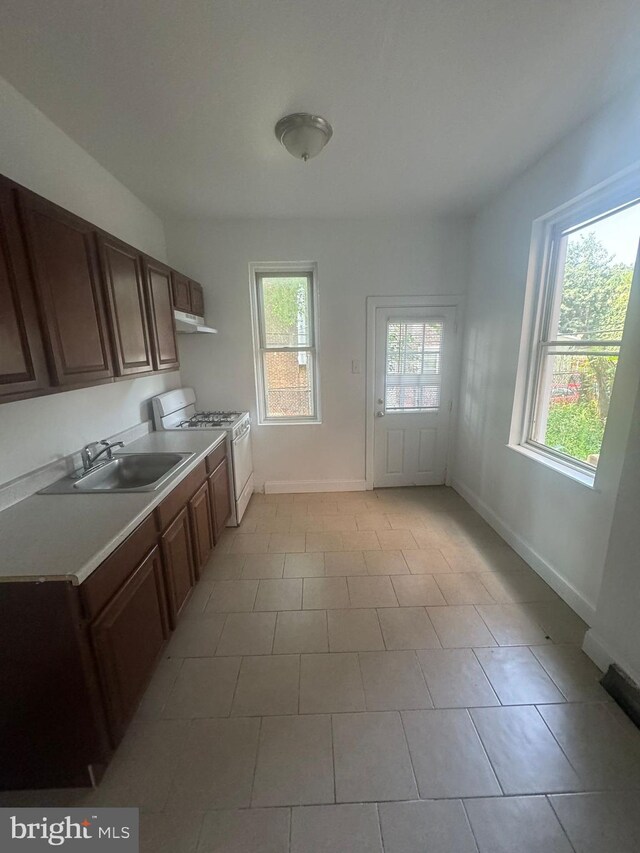 kitchen with sink, white range with gas stovetop, and light tile patterned floors