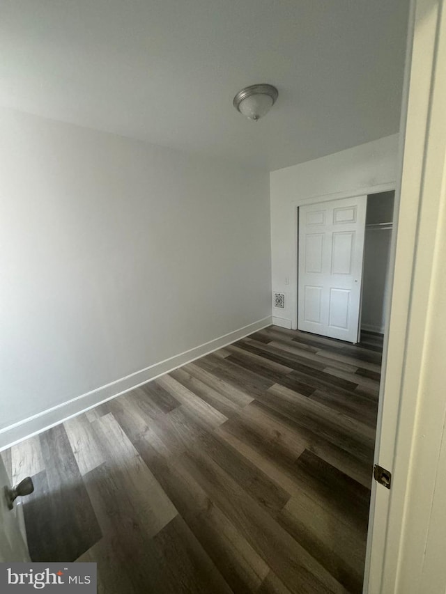 unfurnished bedroom featuring dark hardwood / wood-style flooring and a closet