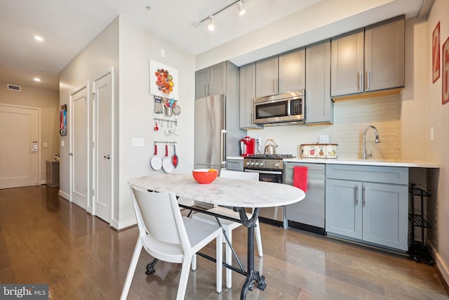 kitchen featuring gray cabinets, high end appliances, dark hardwood / wood-style floors, and backsplash