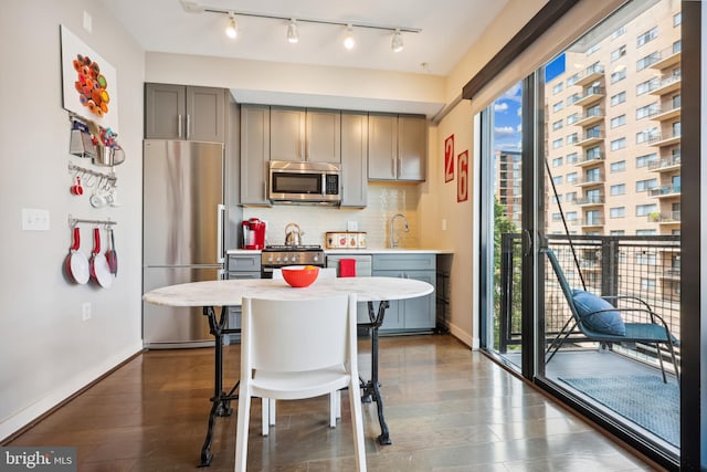 kitchen featuring gray cabinets, appliances with stainless steel finishes, tasteful backsplash, sink, and a breakfast bar area