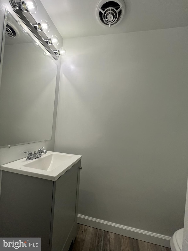 bathroom with vanity, toilet, and hardwood / wood-style flooring