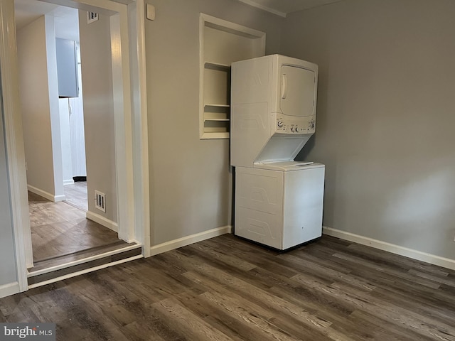 laundry area featuring laundry area, baseboards, visible vents, stacked washer and clothes dryer, and dark wood-type flooring