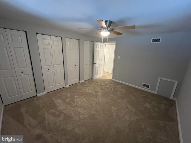 unfurnished bedroom featuring carpet flooring, ceiling fan, and two closets