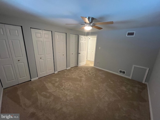 unfurnished bedroom featuring two closets, ceiling fan, and carpet