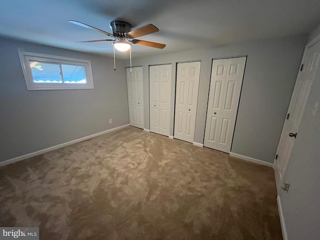 unfurnished bedroom with two closets, ceiling fan, and carpet floors