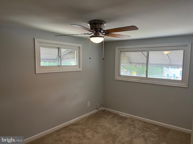 carpeted spare room with baseboards, ceiling fan, and a healthy amount of sunlight