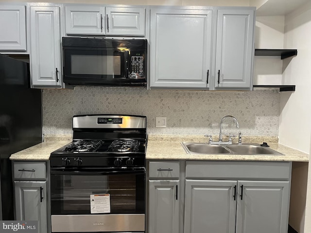 kitchen featuring white cabinets, black appliances, light countertops, and a sink