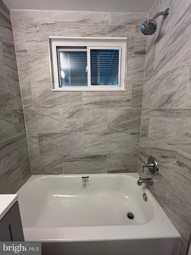 bathroom featuring tiled shower / bath combo and vanity