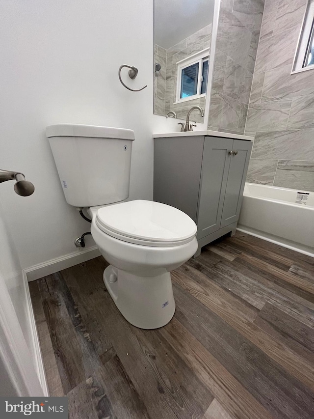 full bathroom with hardwood / wood-style floors, toilet, tiled shower / bath combo, and vanity