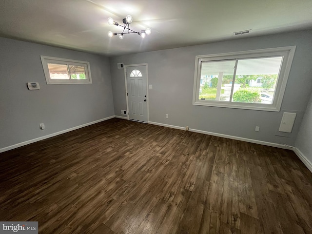 entrance foyer with dark wood-style floors, visible vents, a notable chandelier, and baseboards