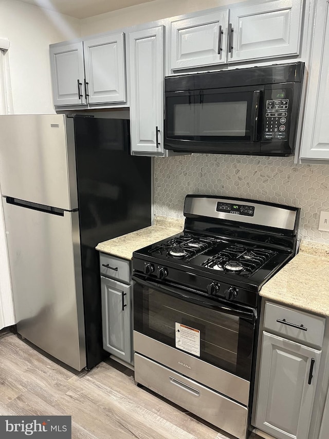 kitchen featuring light hardwood / wood-style floors, appliances with stainless steel finishes, white cabinets, and decorative backsplash